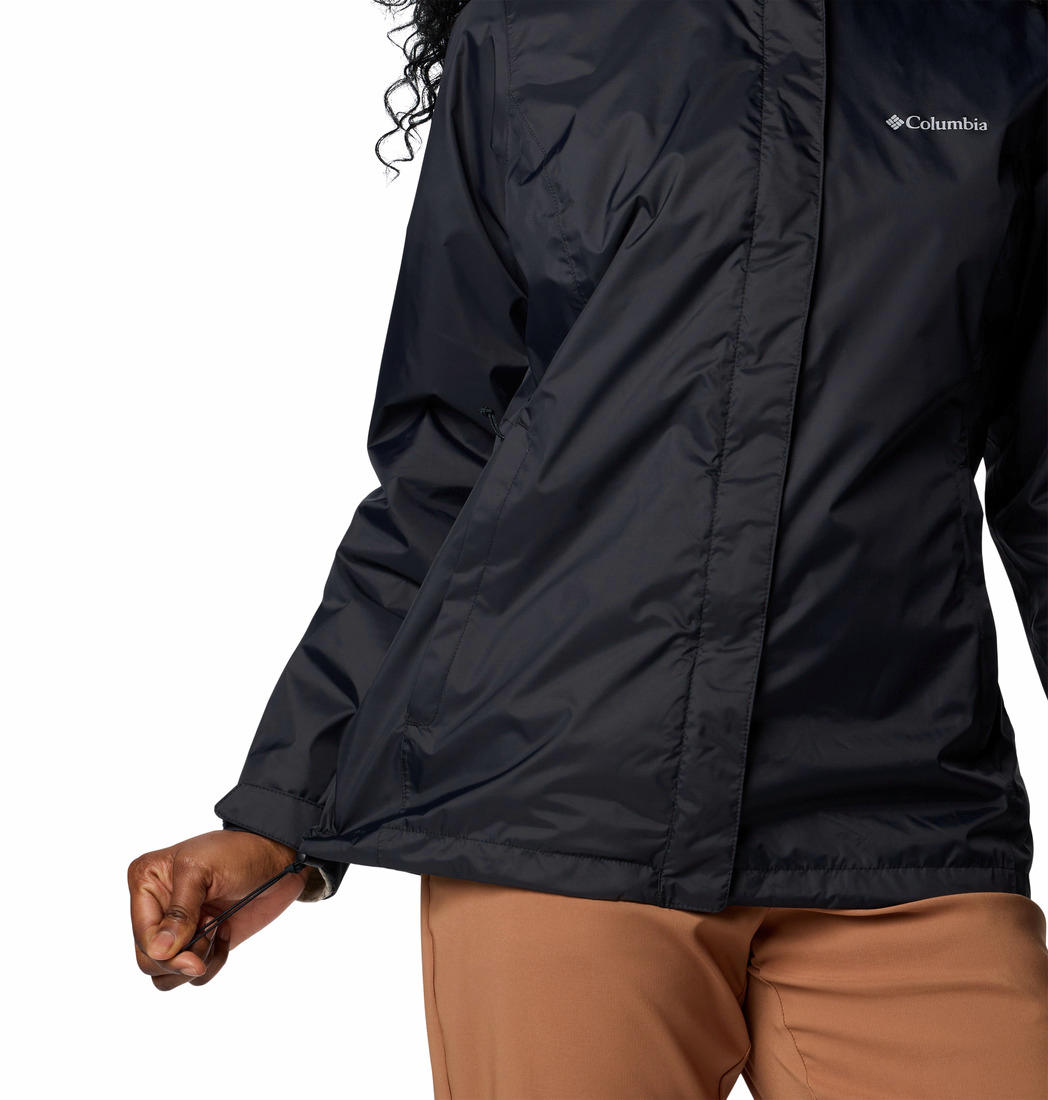 A woman wearing a black Columbia branded waterproof rain jacket with a hood, suitable for hiking.