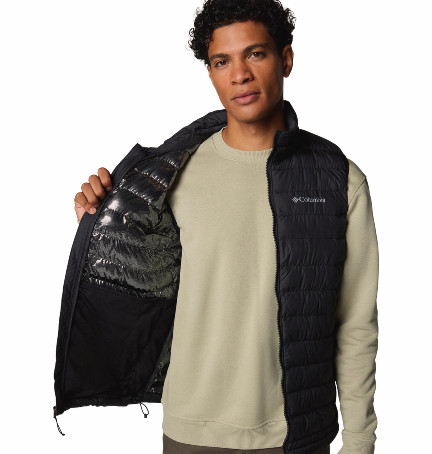 A man wearing a black Columbia Men's Black Omni-Heat Reflective Powder Lite II Vest over a beige long-sleeve shirt paired with brown pants.