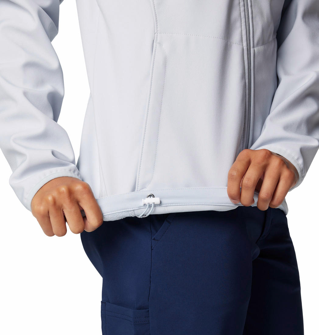 A woman wearing a grey full-zip Columbia softshell jacket with adjustable cuffs and hem, and zippered pockets on the sides.